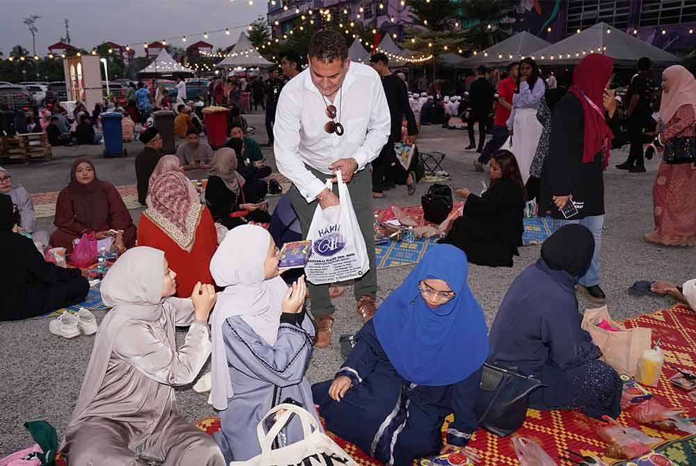Igram (berdiri) turut membantu sebagai sukarelawan dalam mengagihkan makanan yang disediakan kepada pengunjung Iftar Ala Madinah @ Karangkraf pada Rabu.