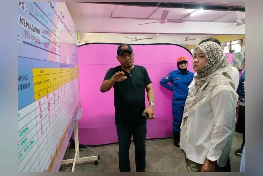 Fadhlina (kanan) mendengar taklimat mengenai mangsa banjir yang dipindahkan di PPS SK Seri Kencana, Simpang Renggam, Kluang pada Jumaat.