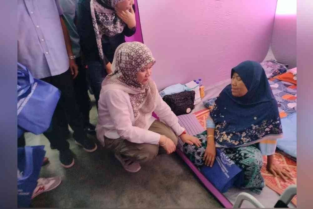 Fadhlina (kiri) bertanya khabar mangsa banjir yang dipindahkan di PPS SK Seri Kencana, Simpang Renggam, Kluang pada Jumaat.