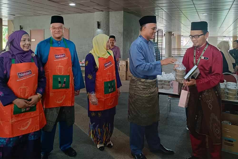 Isham (dua dari kanan) mengagihkan bubur lambuk kepada kakitangan KPKM di pekarangan Dewan Serbaguna Wisma Tani, KPKM di sini pada Jumaat.