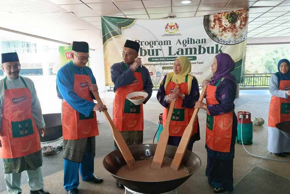 Dua dari kiri: Mohd Jazri, Isham, Noor Laili dan Lailah melakukan gimik mengacau bubur lambuk di pekarangan Dewan Serbaguna Wisma Tani, KPKM pada Jumaat.