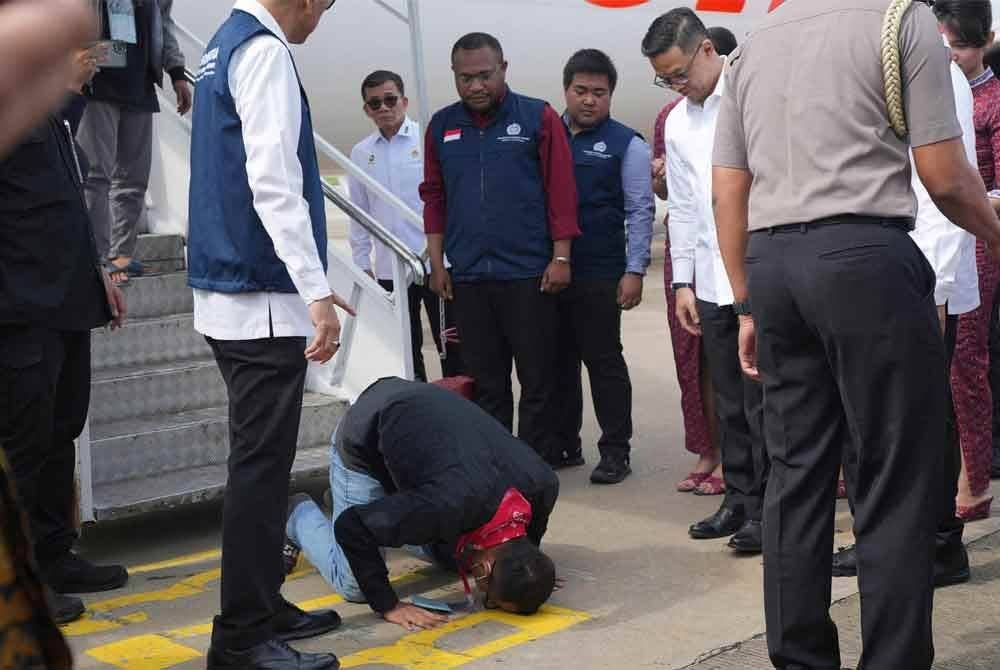 Seorang warganegara Indonesia yang pernah bekerja di pusat penipuan di Myanmar melakukan sujud syukur sebaik tiba dari Thailand di Lapangan Terbang Antarabangsa Soekarno-Hatta, Tangerang, Banten. Foto AFP