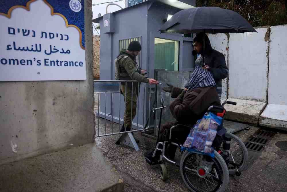 Seorang lelaki Palestin menjalani pemeriksaan kad pengenalan untuk melepasi pusat pemeriksaan Israel di Bethlehem, Tebing Barat, ketika jemaah menuju ke pekarangan Masjid Al-Aqsa di Kota Lama Baitulmaqdis bagi menunaikan solat Jumaat. Foto AFP