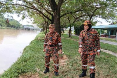 Siti Rohani (kanan) bersama Azmi melihat paras air Sungai Pandan yang menurun berbanding semalam.