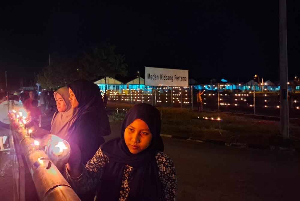 Dhia Humaira Mohammad Farid, 14, (kanan) bersama dua rakannya Nurfarah Aqilah Nazri, 17, dan Nuramirah Nazri, 15, membantu menyalakan pelita panjut di kawasan perumahan mereka.