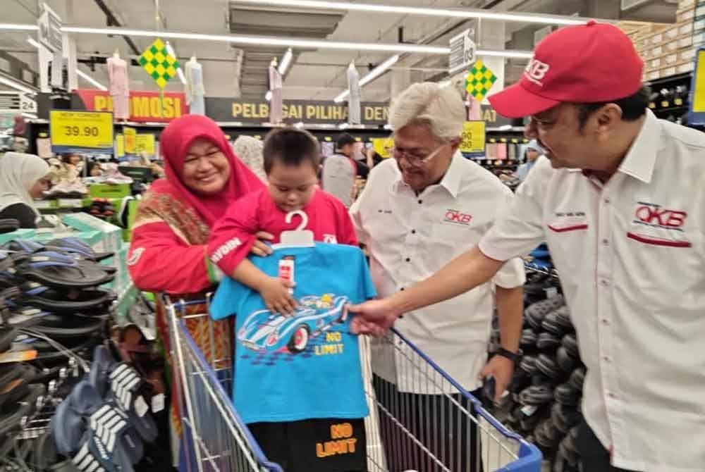 Nik Izani (dua, kanan) melihat pakaian baharu yang dibeli penerima sumbangan.