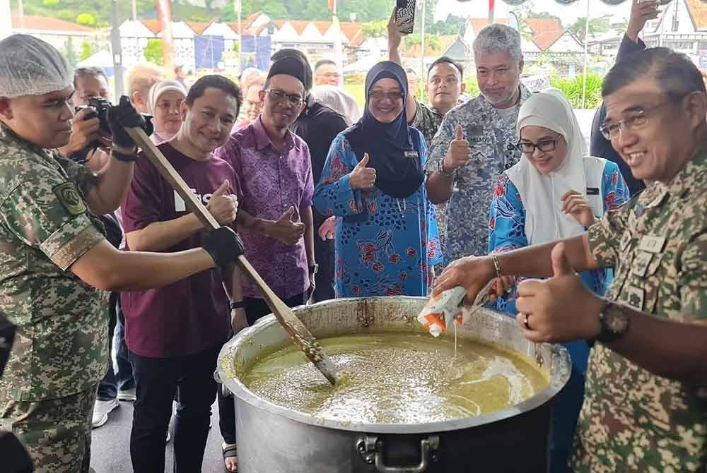 Mohd Nizam (kanan) dan Syamil (dua dari kiri) bersama-sama bergotong-royong menyiapkan bubur lambuk.