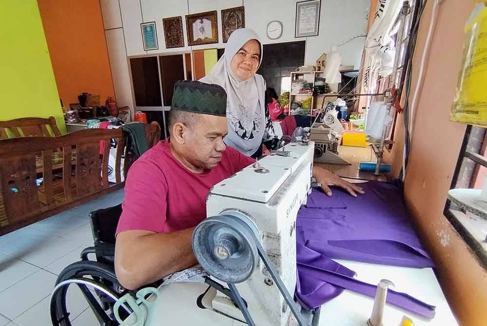 Mohd Razak bersama Maslinda menyiapkan baju raya ditempah pelanggan.