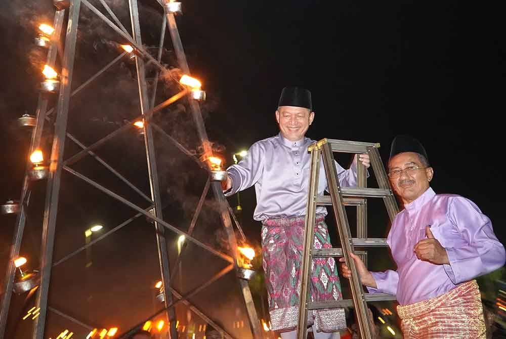 Razali (kiri) bersama Tun Faisal menghidupkan pelita raya sempena program Peliter@Perasing di R&R Perasing pada malam Jumaat.