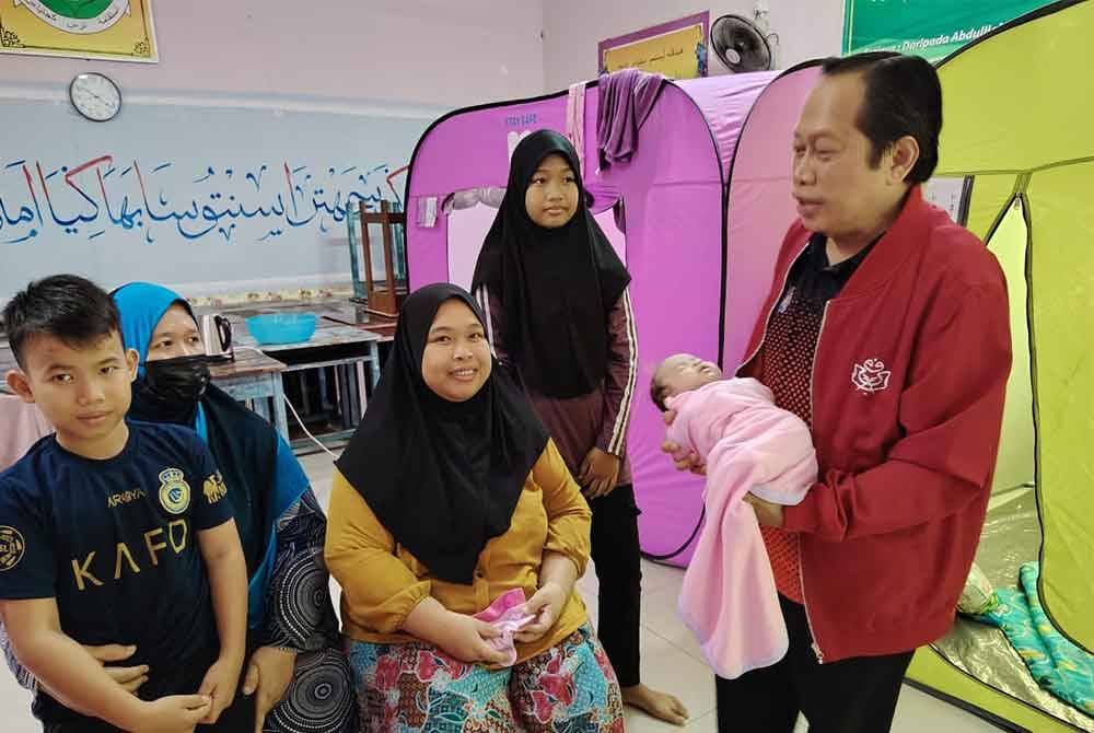 Ahmad (kanan) melawat mangsa banjir di PPS Sekolah Agama Kayu Ara Pasong, Pontian.