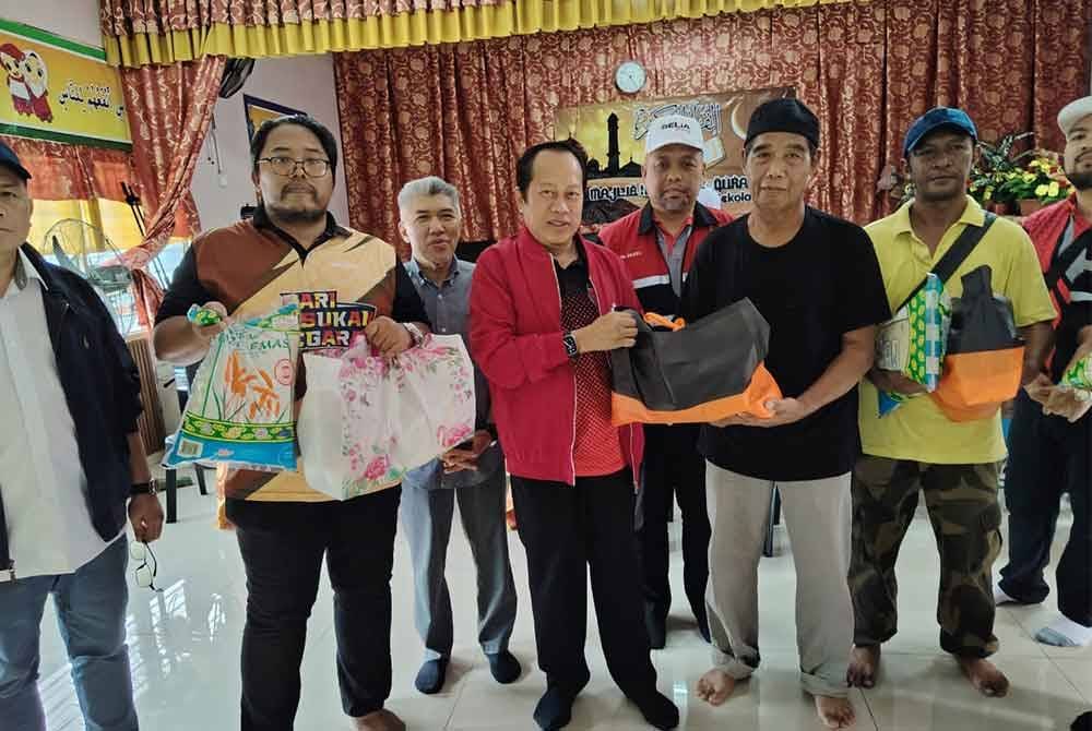 Ahmad (tiga dari kiri) menyerahkan sumbangan kepada mangsa banjir di PPS Sekolah Agama Kayu Ara Pasong, Pontian.