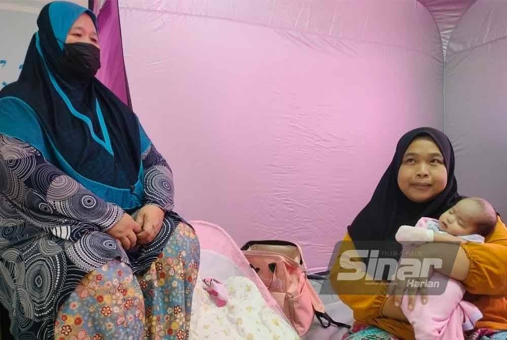 Siti Amyra (kanan) memangku bayinya yang berusia 30 hari di PPS Sekolah Agama Kayu Ara Pasong, Pontian.