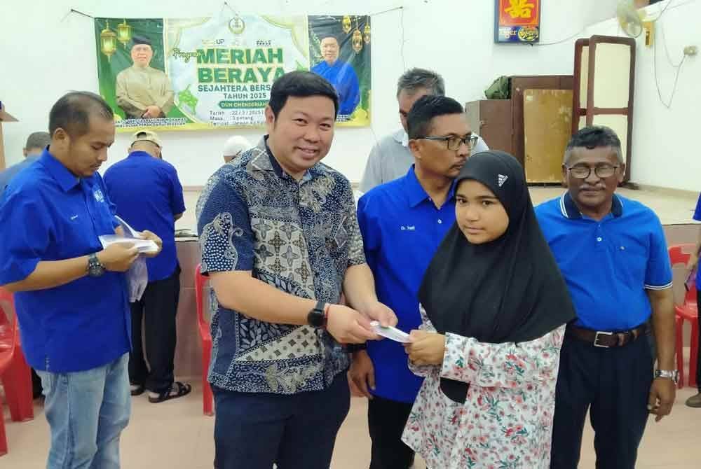 Shin Heng (dua dari kiri) menyampaikan baucar sumbangan kepada penerima sempena Program Meriah Beraya Sejahtera Bersama DUN Chenderiang di Dewan Kampung Pahang pada Sabtu.