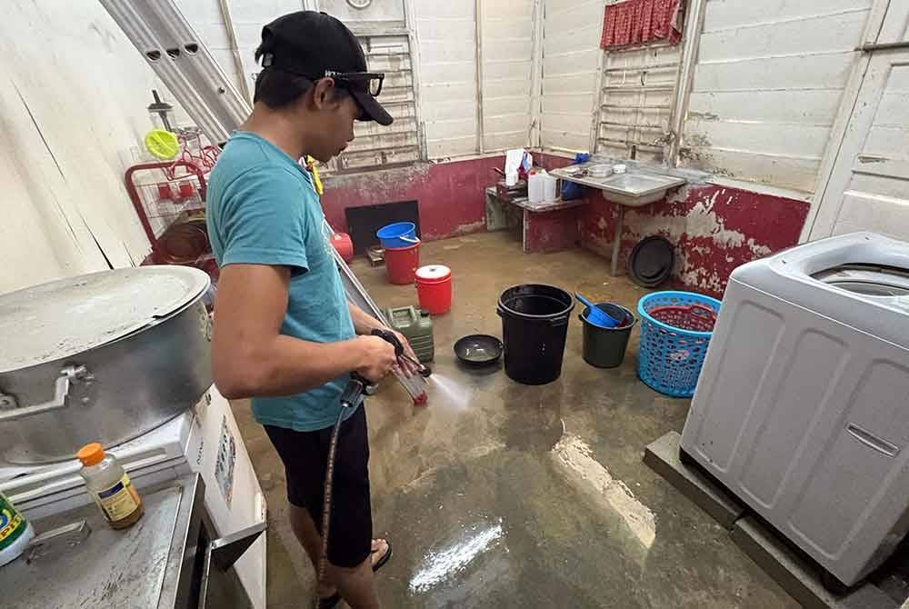 Mohd Afrizat Hamrizan, 33, membersihkan rumahnya pada Sabtu selepas banjir surut sepenuhnya ketika tinjauan di Kampung Kelantan. Foto Bernama
