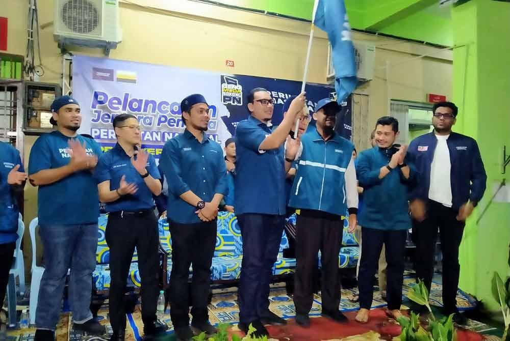 Afnan Hamimi (tengah) menyempurnakan gimik Pelancaran Jentera Pilihan Raya Pemuda PN N.48 Ayer Kuning di sini pada malam Sabtu.