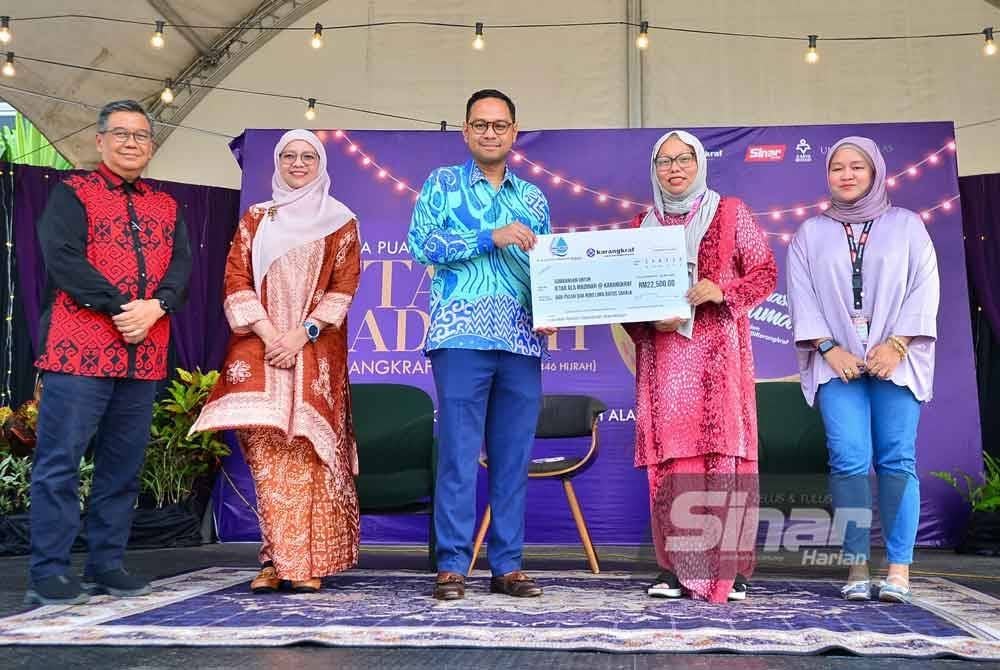 Azlan Shah (tengah) menyerahkan replika cek kepada Firdaus (dua, kanan) di Dataran Karangkraf, Shah Alam pada Jumaat.