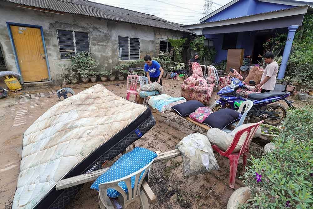 Mangsa banjir Ros Mela Abd Gani (tengah), 55, bersama anak-anaknya Muhammad Shahrudin Mohd Naser (kiri), 27, dan Muhammad Sharul Aiman (kanan), 19, mengeluarkan perabot-perabot yang rosak di rumahnya akibat banjir besar yang melanda Johor 19 Mac lalu, ketika tinjauan di Kampung Pasir Tebrau hari ini.