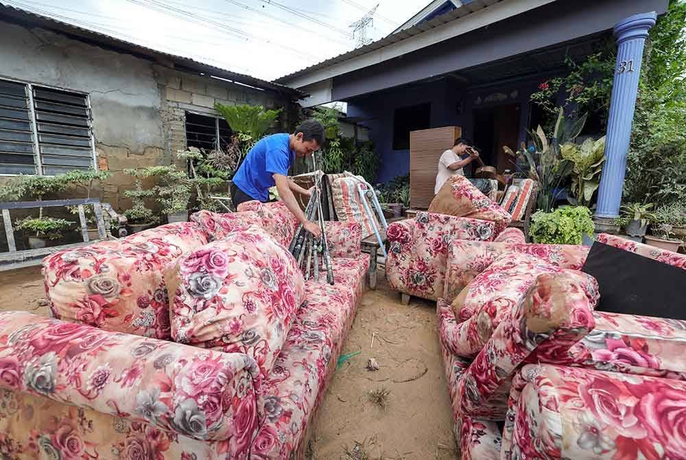 Mangsa banjir Muhammad Shahrudin Mohd Naser (kiri), 27, bersama adiknya Muhammad Sharul Aiman, 19, mengeluarkan perabot-perabot yang rosak akibat banjir besar yang melanda Johor 19 Mac lalu, ketika tinjauan di Kampung Pasir Tebrau hari ini.