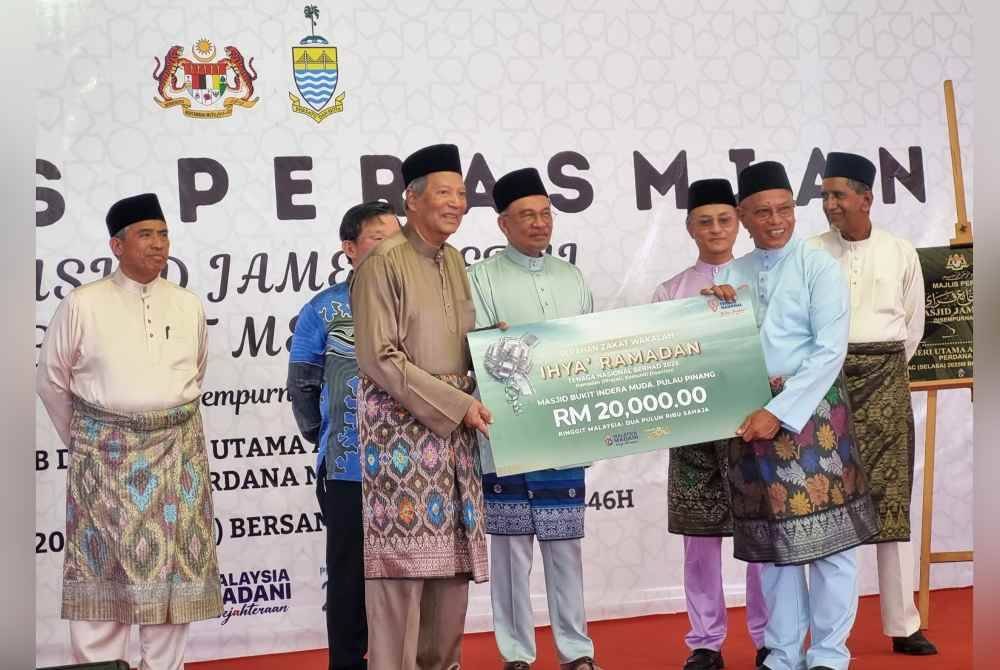 Abdul Razak (depan, kiri) menyampaikan sumbangan zakat wakalah sebanyak RM20,000 kepada wakil Masjid Bukit Indera Muda sambil disaksikan oleh Anwar (tengah) ketika perasmian Masjid Jamek Perai, Pulau Pinang pada 18 Mac lalu.