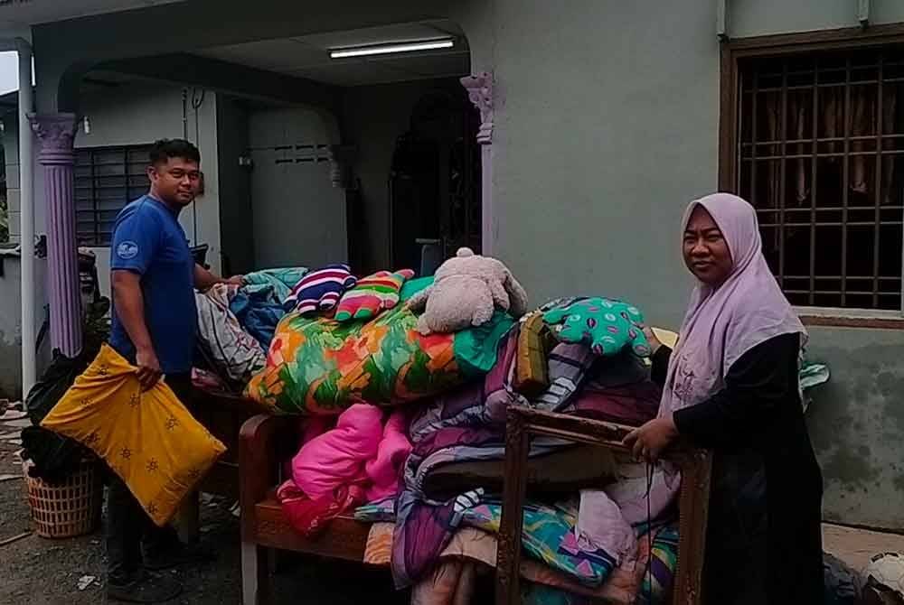 Nor Hamizah (kanan) dan Asnawi menunjukkan barang rumah rosak akibat banjir.