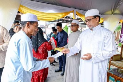 Mohd Anis (kanan) menyampaikan sumbangan kepada mualaf.