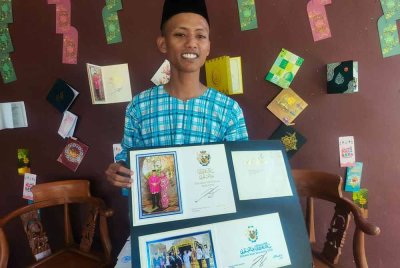 Muhammad Azim menunjukkan kad hari raya yang diterimanya dari Yang di-Pertuan Agong Sultan Ibrahim Sultan Iskandar pada tahun lalu.