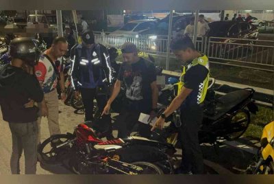 Anggota trafik memeriksa salah sebuah motosikal yang ditahan.