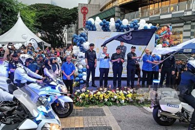 Mohd Yusri (depan) memegang bendera Sang Saka Biru melakukan gimik pelancaran Program Advokasi Op Selamat 24 Sempena Hari Raya Aidilfitri 2025 di Jalan Tunku Abdul Rahman, Kuala Lumpur pada Ahad.