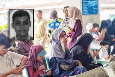 Jamilah (tengah) menunggu proses bedah siasat anak sulungnya di Jabatan Perubatan Forensik Hospital Melaka, di Melaka, pada Ahad.