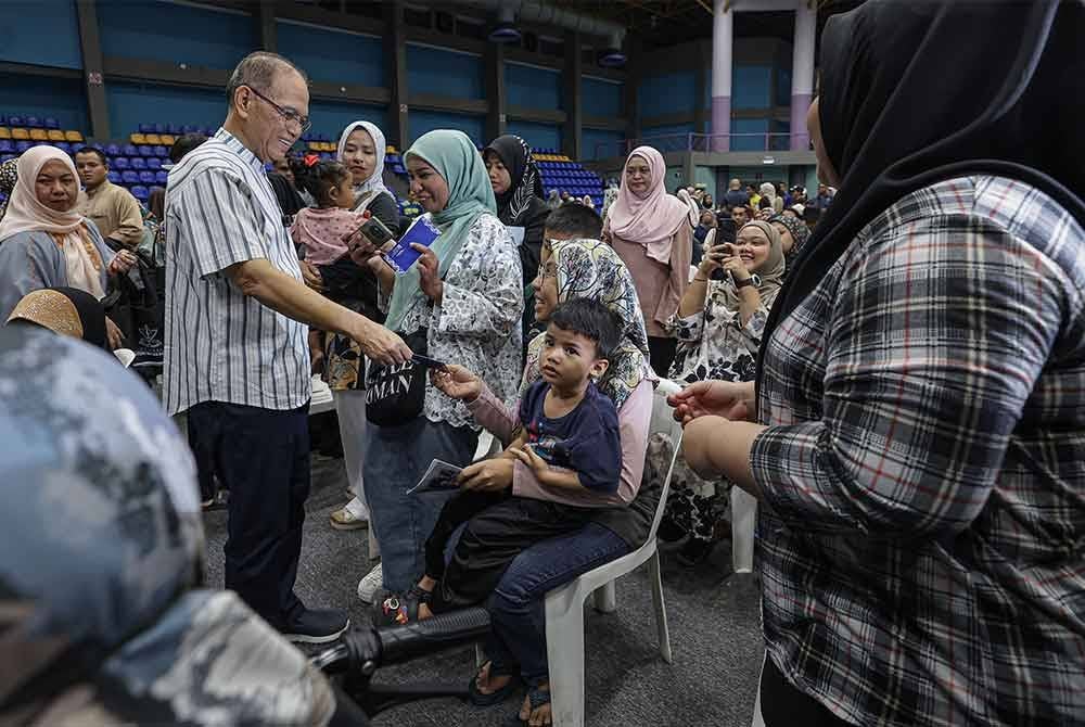Wan Rosdy beramah mesra sambil menyampaikan sumbangan kepada pengunjung yang terdiri daripada anak jati Pahang pada Majlis Penyerahan Baucar Moh Balik Raya Ke Pahang 2025 di Stadium Titiwangsa hari ini. - Foto: Bernama