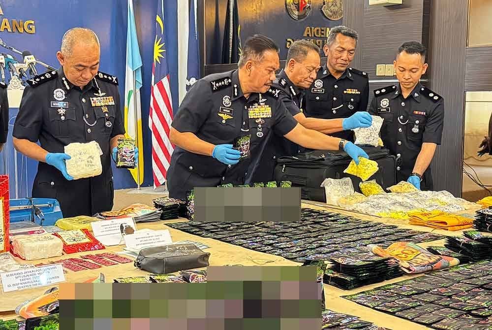 Hamzah (dua dari kiri) menunjukkan dadah yang dirampas daripada pasangan suami isteri tersebut.