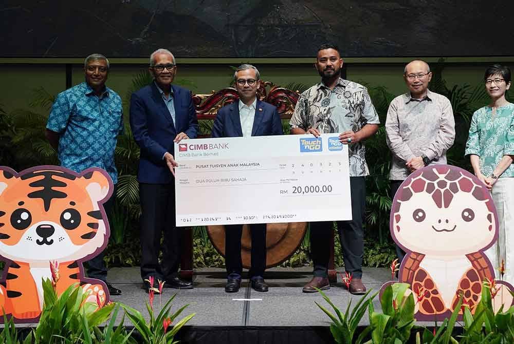 Penyerahan replika cek oleh Fahmi (tengah) dan Mohd Nasir (dua dari kiri) kepada Pusat Tuisyen Anak Malaysia yang disaksikan oleh Abdul Wahid (dua dari kanan) pada majlis pelancaran Charms For Change pada Isnin.