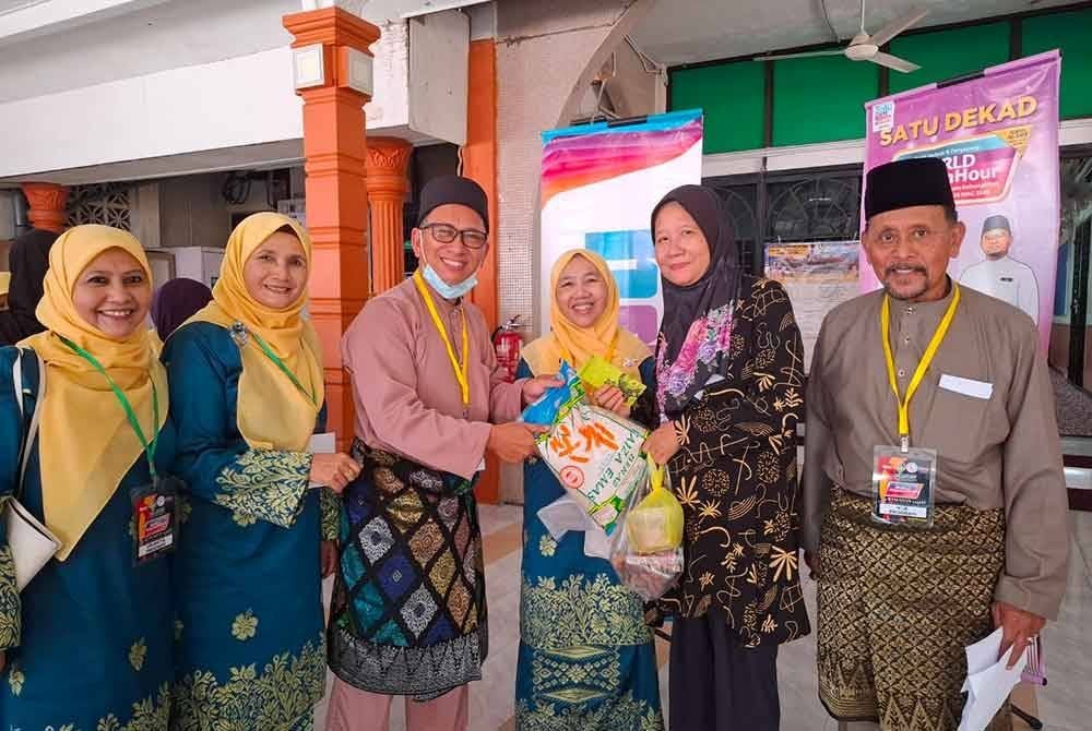 Pengerusi Rumah Ngaji Perak, Robaatun Hadayiah Harun (empat dari kiri) menyampaikan bantuan kepada 20 ibu tunggal berupa beras dan duit raya sumbangan Rumah Ngaji Perak.