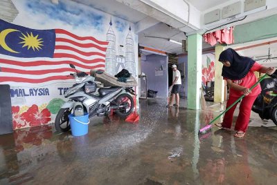 Mangsa banjir giat membersihkan lantai kawasan rumahnya yang dinaiki banjir besar ketika tinjauan di Blok 22 PPR Desa Mutiara, Bandar Dato Onn - Foto: Bernama