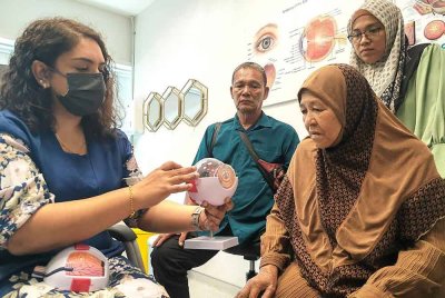 Astiah (duduk) ditemani Mohd Noor dan anaknya membuat pemeriksaan mata di Hospital Columbia Asia di Seremban.