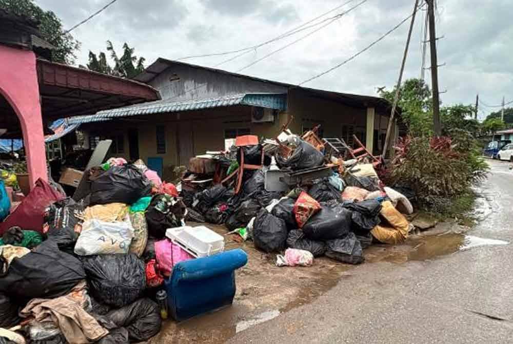 Pelbagai barangan yang musnah akibat bencana bah dilonggokan mangsa banjir di hadapan rumah untuk dikutip oleh syarikat konsesi ketika tinjauan di Kampung Seri Serdang, baru-baru ini. Foto fail Bernama