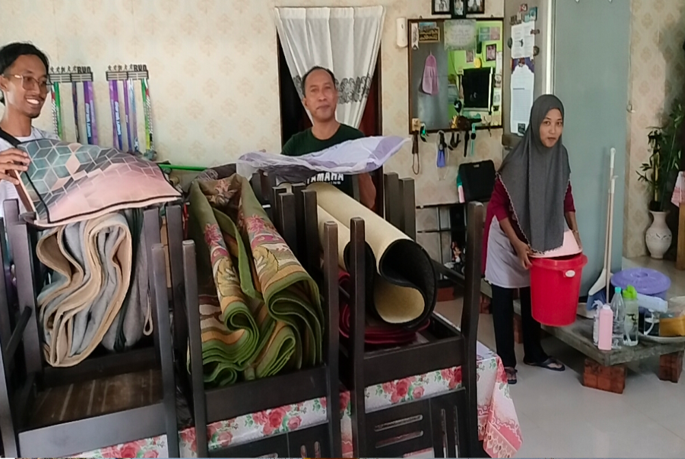Abdul Rahim (tengah) bersama isteri, Kamariah (kanan) mengemas rumah selepas dibenarkan pulang dari PPS pada pagi RabU.