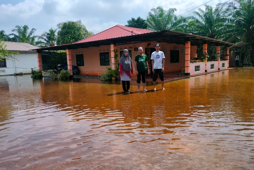 Abdul Rahim (tengah) menunjukkan rumahnya yang kini dilanda banjir temenung.