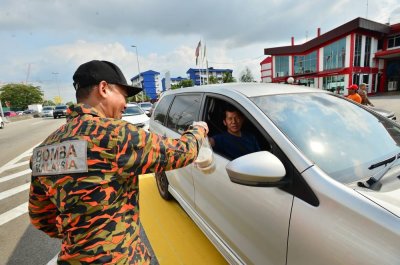 Anggota bomba mengagihkan bubur lambuk kepada komuniti masyarakat setempat.