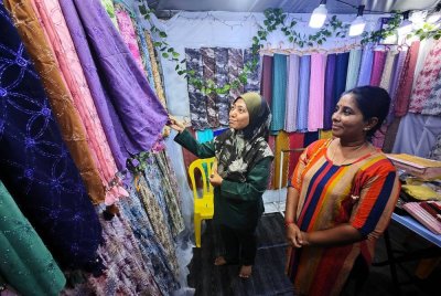 Mariyai Devi melayan pelanggan nya yang sedang memilih selendang dijualnya.