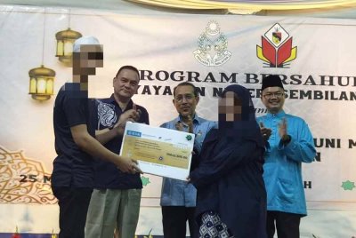 Jamil (kiri) menyerahkan sebahagian wang hasil bekerja sebanyak RM12,000 kepada isterinya pada Program Bersahur Yayasan Negeri Sembilan bersama ODS di PRP Mantin pada Selasa.