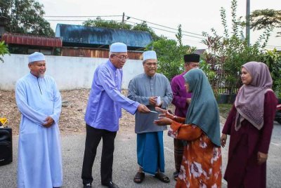 Mahdzir (dua dari kiri) menyampaikan sumbangan Aidilfitri kepada penduduk di Felda Bukit Tembaga, di sini pada Selasa.