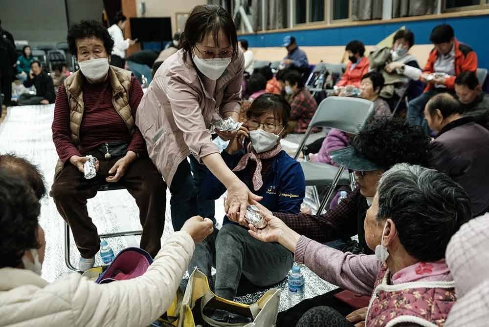 Sukarelawan mengagihkan kimbap (nasi gulung) kepada penduduk yang dipindahkan di pusat penempatan sementara di sebuah sekolah di Andong.