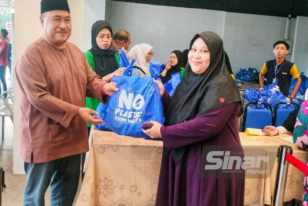 Ismail Mohamed (kiri) menyerahkan goodies kepada pengunjung.