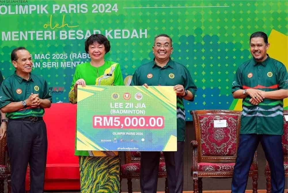 Muhammad Sanusi (dua dari kanan) menyerahkan replika cek ganjaran kepada ibu Lee Zii Jia, Leow Siet Peng di Seri Mentaloon pada Rabu.