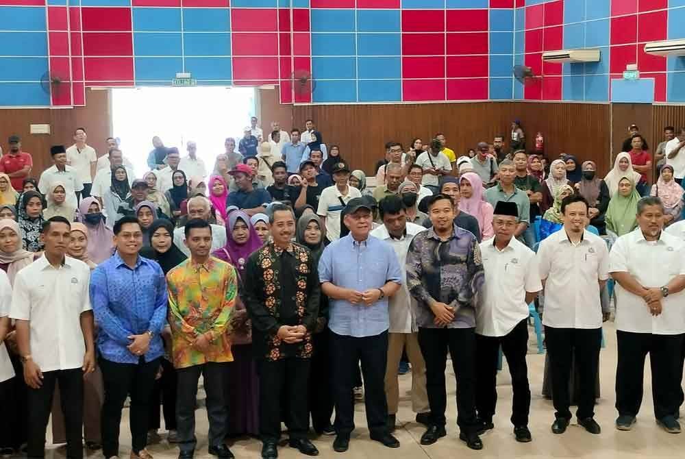 Hasni (lima dari kanan) bersama penduduk Benut yang menerima sumbangan RM3,000 selepas terjejas akibat banjir minggu lalu.