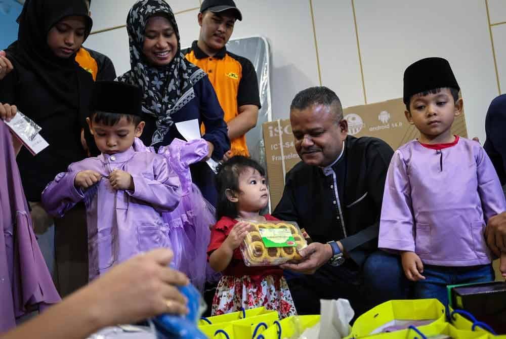 Kadhar Shah (dua, kanan) menyampaikan sumbangan kelengkapan raya dan perabot rumah kepada Farizah Adani (dua, kiri) yang mempunyai enam anak pada program Ziarah Kasih Ceriakan Syawal 2025 di Golden Nasmir pada Rabu. Foto Bernama