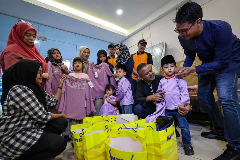 Kadhar Shah (duduk, kanan) bersama Mohd Iskandar (kanan) menyampaikan sumbangan kelengkapan raya dan perabot rumah kepada Farizah Adani yang mempunyai enam anak pada program Ziarah Kasih Ceriakan Syawal 2025 di Golden Nasmir pada Rabu. Foto Bernama