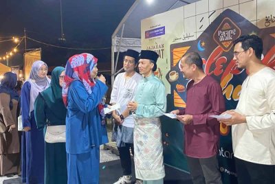 Ahmad Azrin (tiga dari kanan) menyampaikan agihan wakalah zakat kepada penerima sempena program agihan wakalah zakat yang berlangsung di Dataran Payang Walk, di Kuala Terengganu, pada malam Rabu.