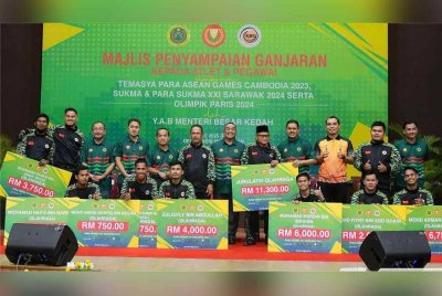 Muhammad Sanusi (tengah) menyerahkan replika cek ganjaran kepada pasukan olahraga yang memenangi pelbagai pingat dalam acara disertai.